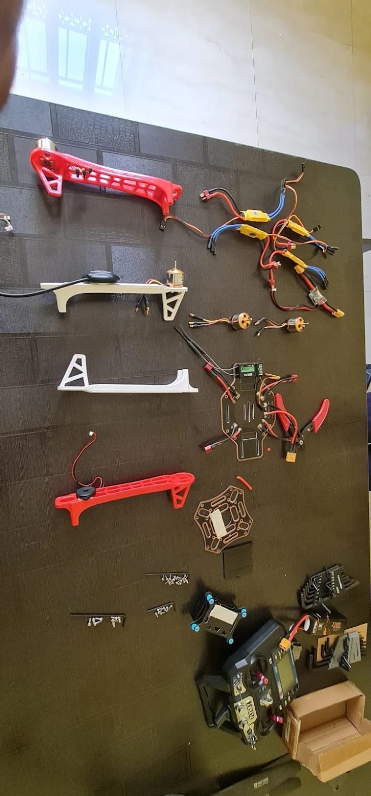 Drone frames, motors, flight controllers and wiring laid out on an assembly workbench