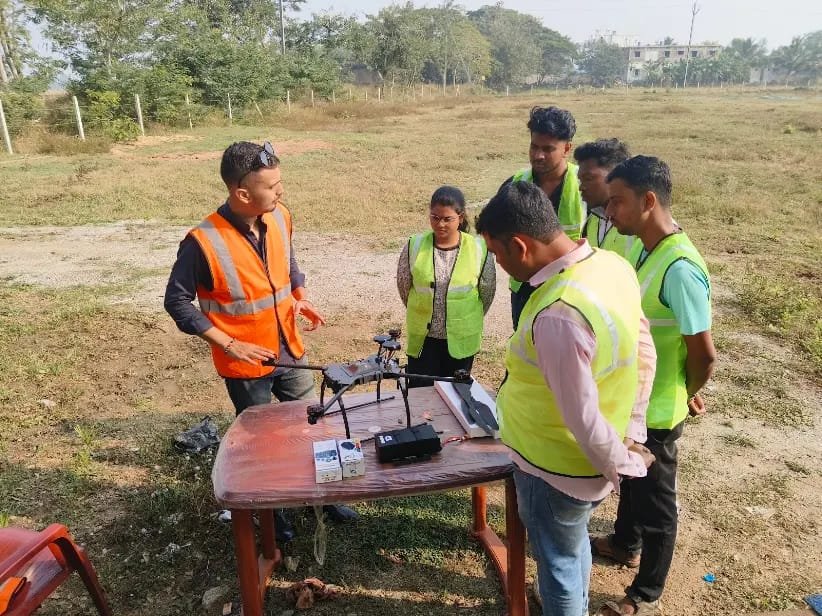 Instructor demonstrating pre-flight checks on a drone to a group of trainees outdoors